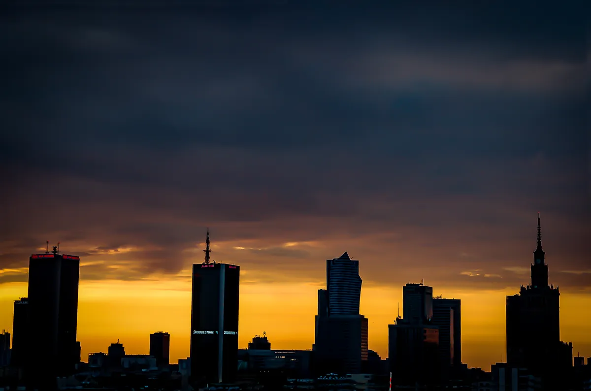 Warsaw skyline silhouetted at sunset with the Palace of Culture and Science at the right edge